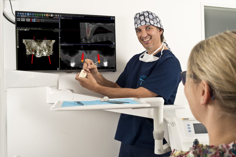 Lutz Feser erklärt einer Patientin die 3D-Implantatplanung am Bildschirm
